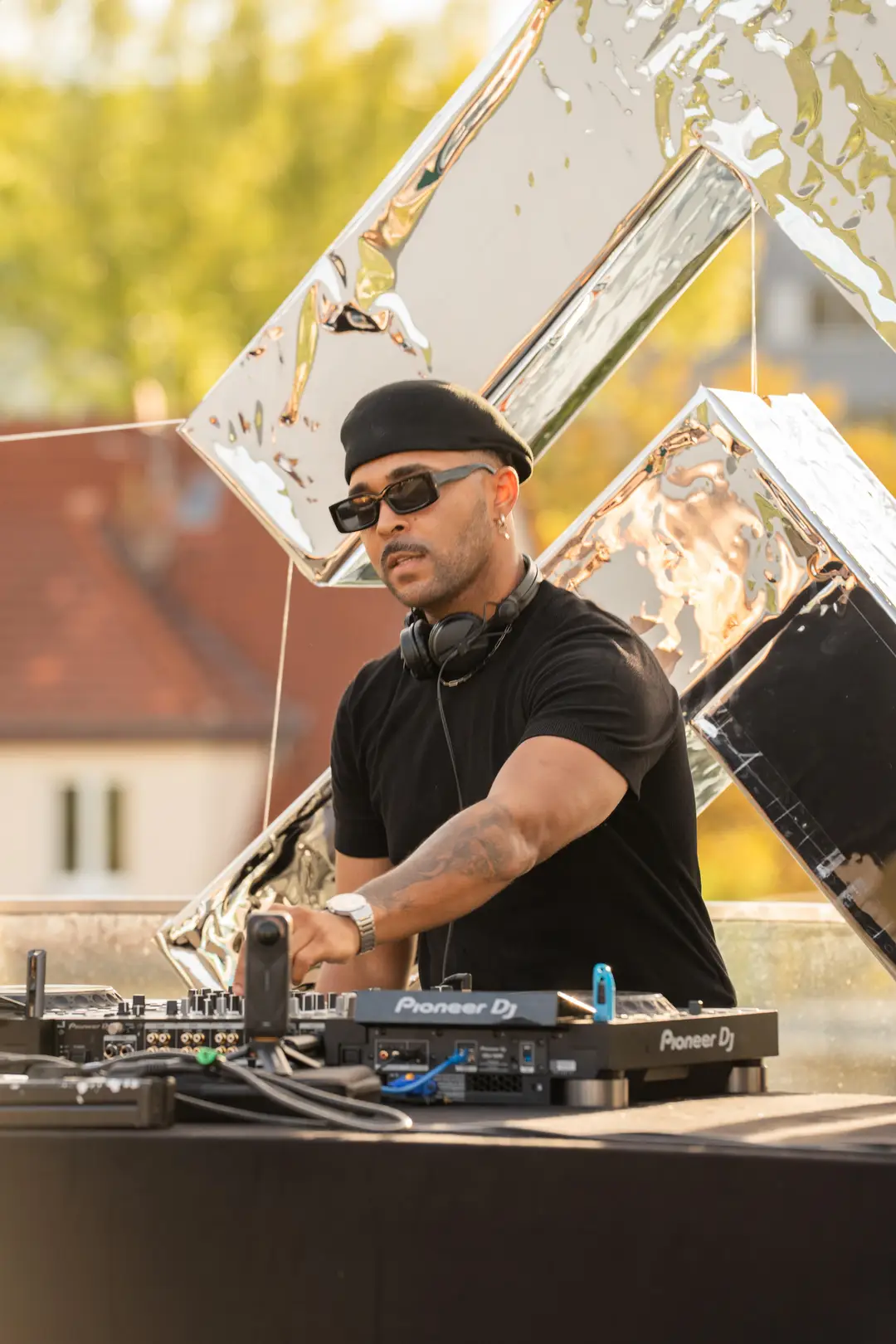 SEKOU reaching across the decks at golden hour, a palm at the edge of the frame